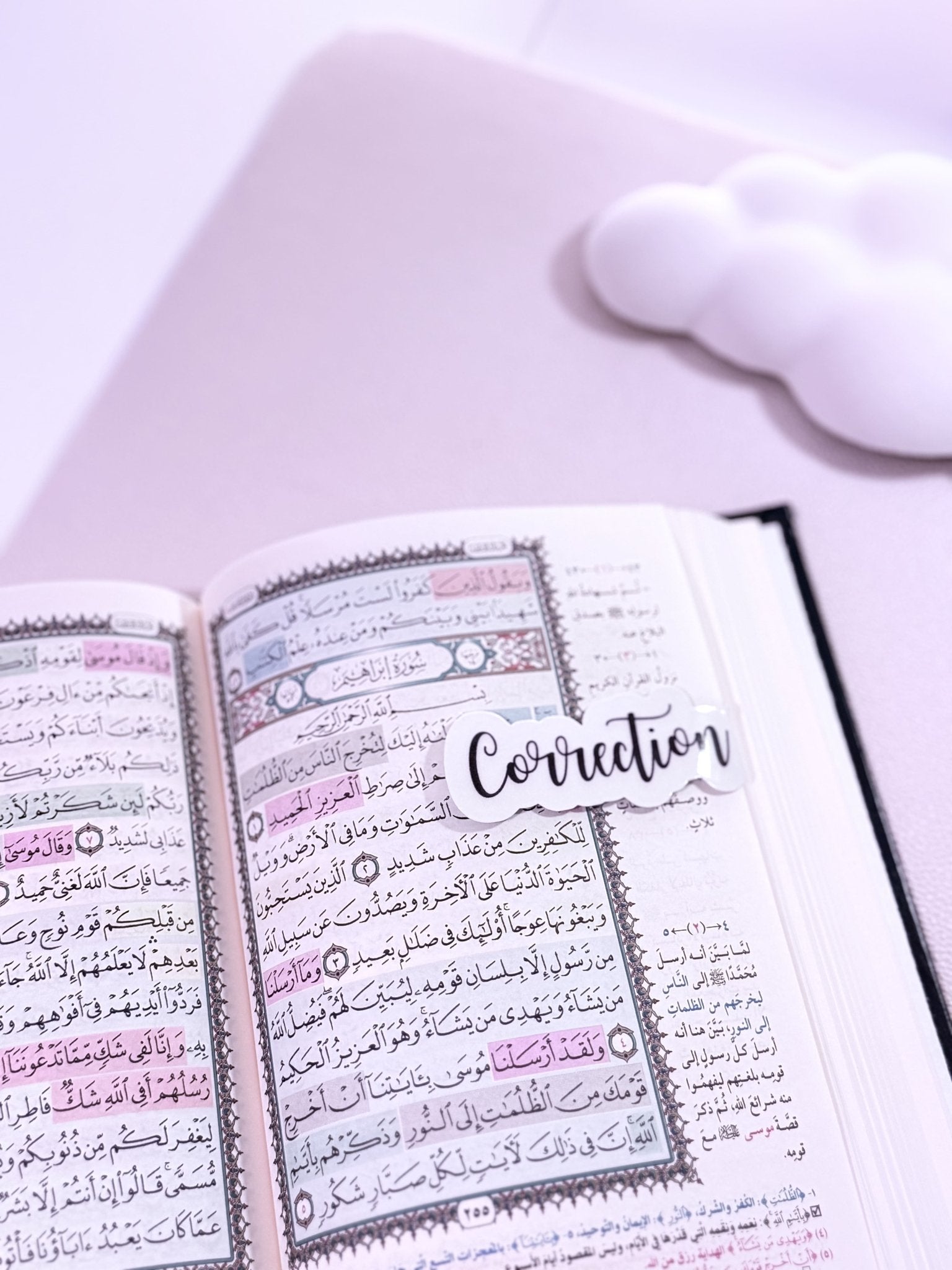 Coran ouvert avec un marque page aimanté écrit noir sur fond blanc "correction"