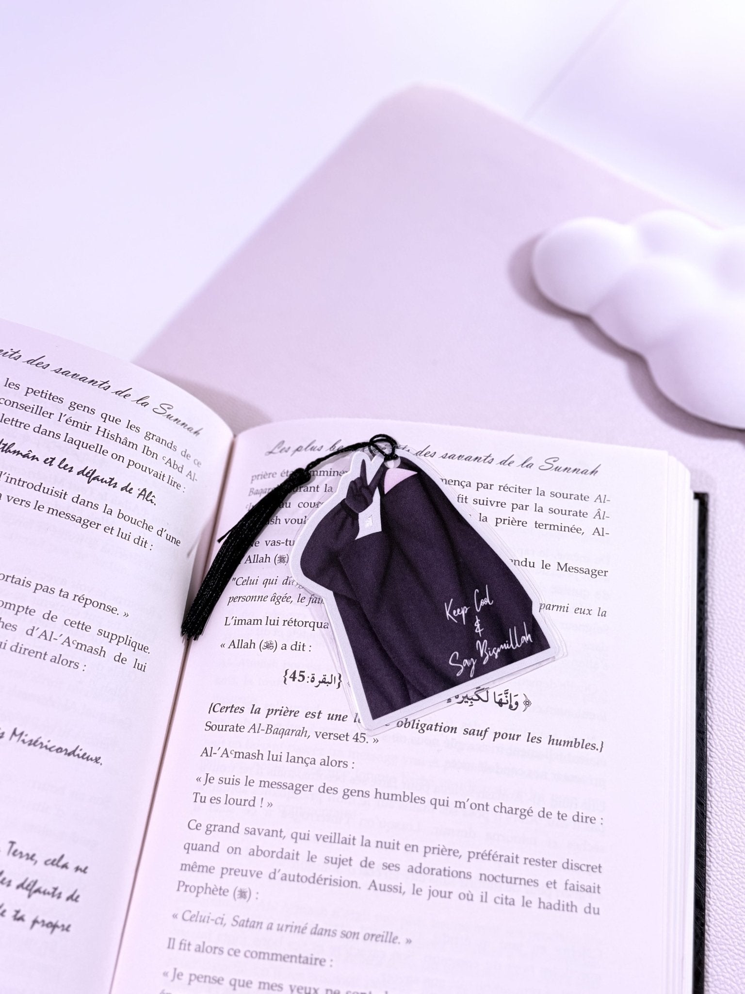 Un marque page d'une fille en niqab habillé en noir avec une phrase de motivation posé sur un livre ouvert