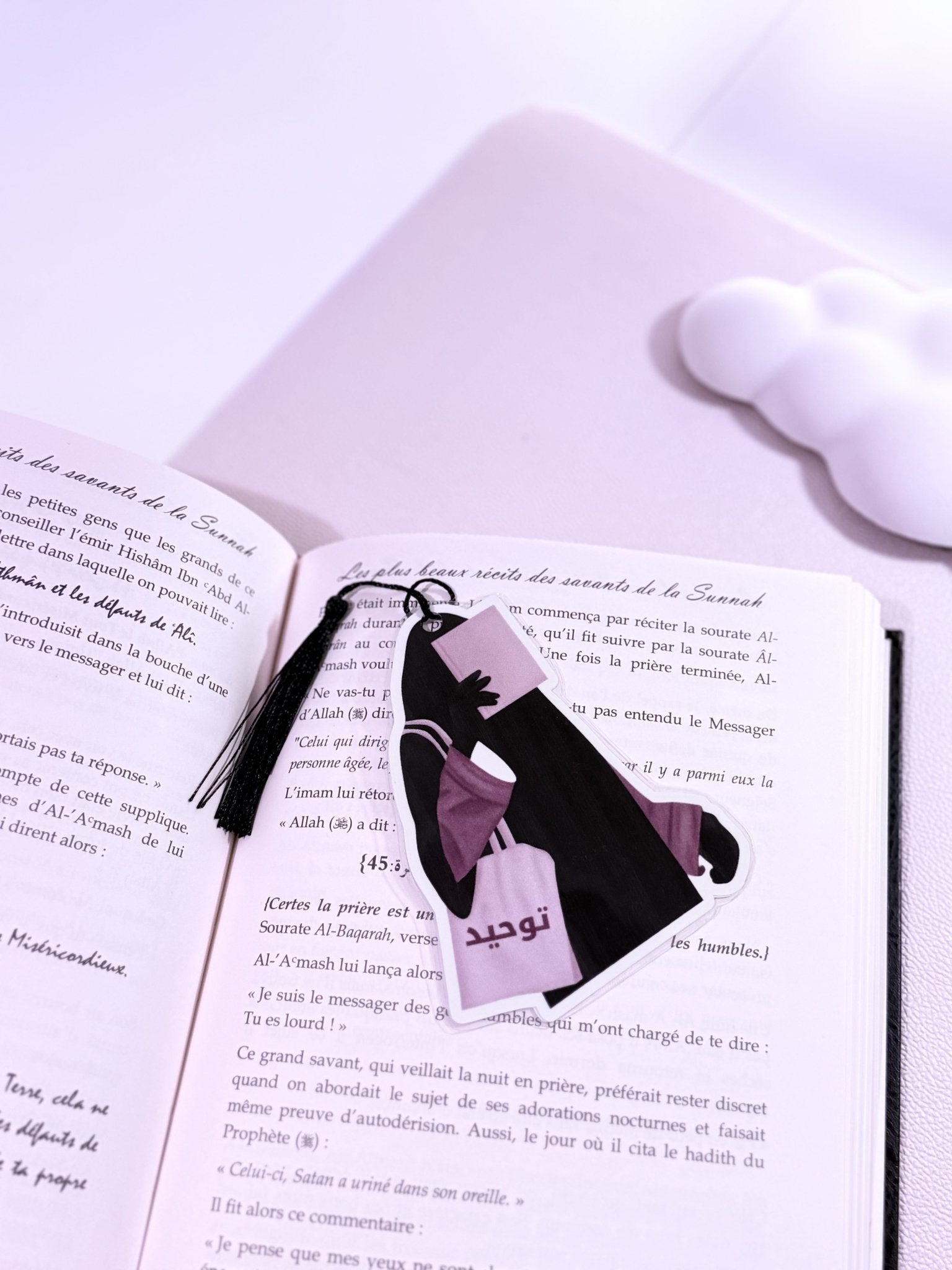 Un marque page d'une hijabi  avec un cordon posé sur un livre ouvert