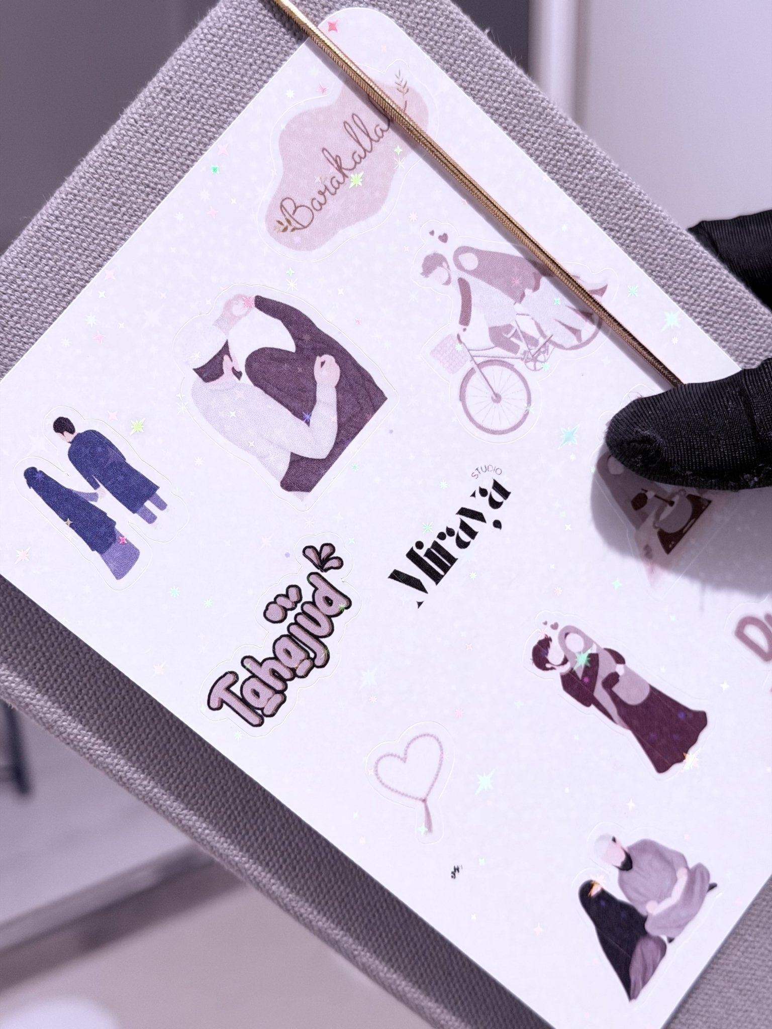 Une main qui présente Une feuille de 10 stickers theme du mariage posé sur un livret gris