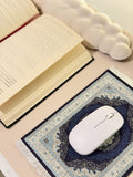 Un tapis de souris bleu nuit motif oriental posé sur un bureau avec un livre ouvert