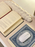 Tapis de souris bleu posé sur un bureau avec un livre ouvert et une souris blanche